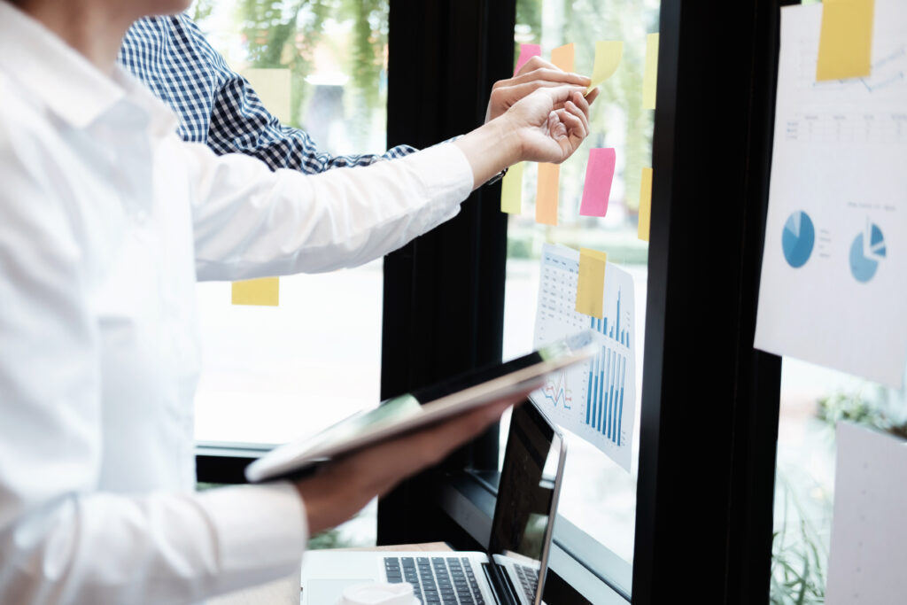 animation organisation séminaire: on voit une femme et un homme qui préparent le séminaire avec des post it collé sur une paroi vitrée